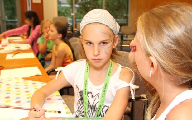 Ein Mädchen bekommt Gesichtsbemalung von einem anderen Mädchen.