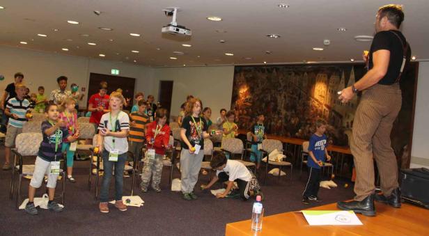 Ein Jongleur zeigt einer Gruppe von Kindern, wie man jongliert.