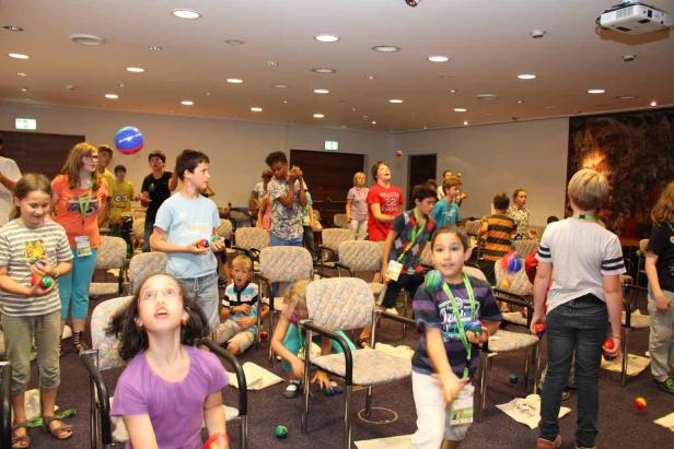 Eine Gruppe Kinder übt Jonglieren in einem hell erleuchteten Raum.