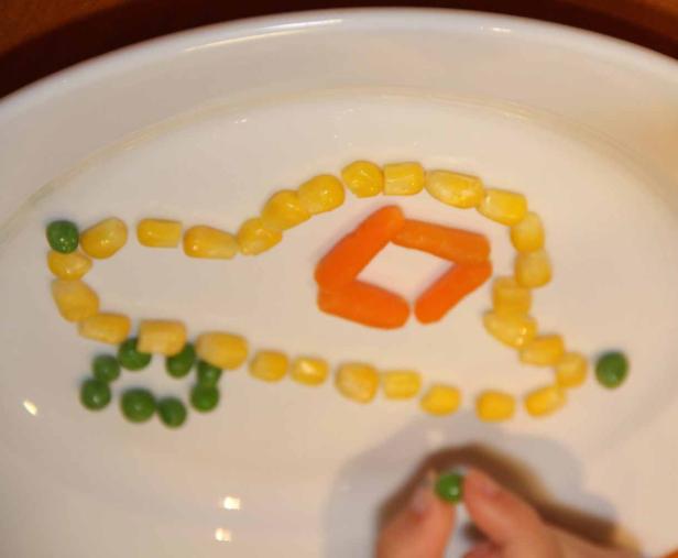 Ein Auto aus Erbsen, Mais und Karotten auf einem Teller.