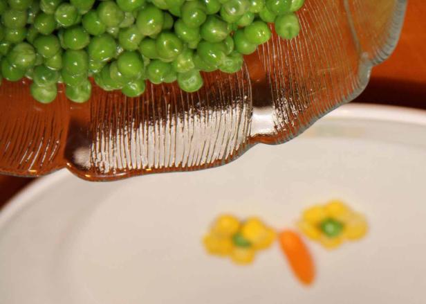 Erbsen werden in die Nähe einer Dekoration aus Gemüse gegossen.