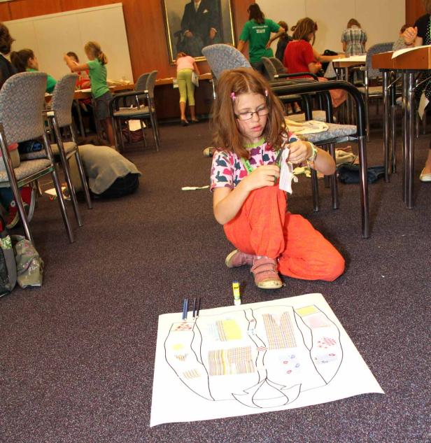 Ein Mädchen sitzt auf dem Boden und bastelt an einem Kunstprojekt.