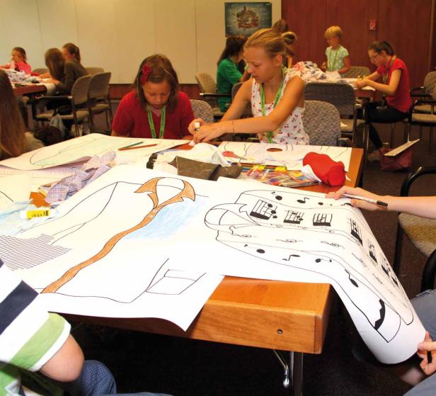 Kinder arbeiten an einem großen Kunstprojekt mit Zeichnungen und Stoffstücken.