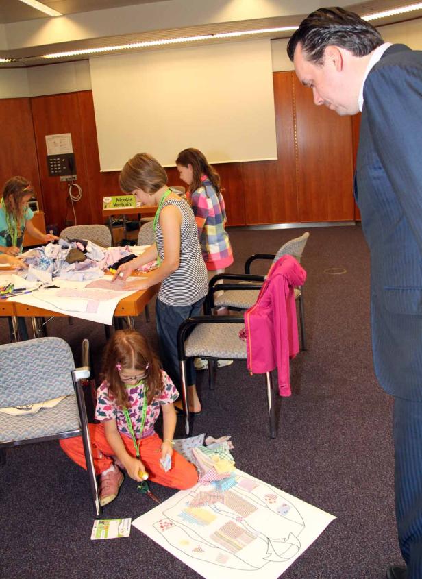 Kinder basteln in einem Raum mit einem Mann im Anzug.