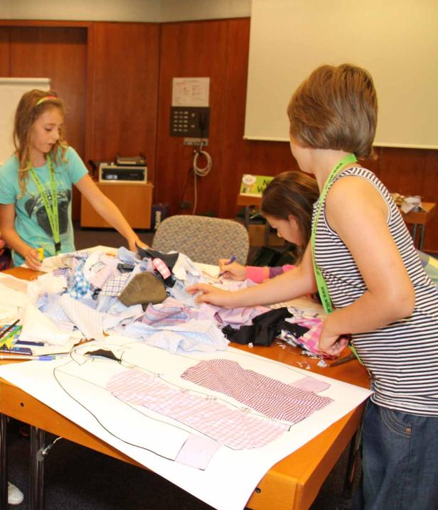Drei Mädchen arbeiten an einem Upcycling-Projekt mit Stoffresten und Schnittmustern.