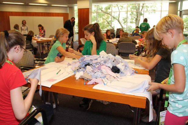 Kinder arbeiten an einem Tisch mit Stoffresten und Schnittmustern.