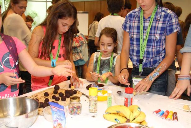 Kinder verzieren Cake Pops mit Schokolade und Zuckerstreuseln.