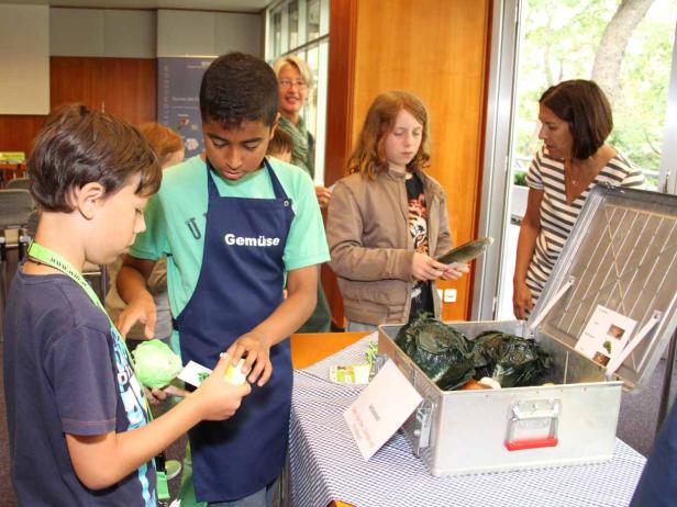 Kinder bereiten Gemüse an einem Stand zu.