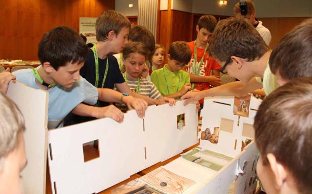 Eine Gruppe Kinder arbeitet an einem Modellhaus.