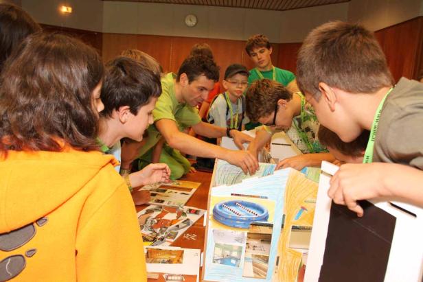 Eine Gruppe von Kindern und ein Betreuer arbeiten an einem Modellhaus.