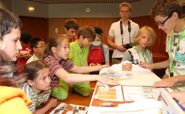 Eine Gruppe Kinder arbeitet an einem Architekturmodell.