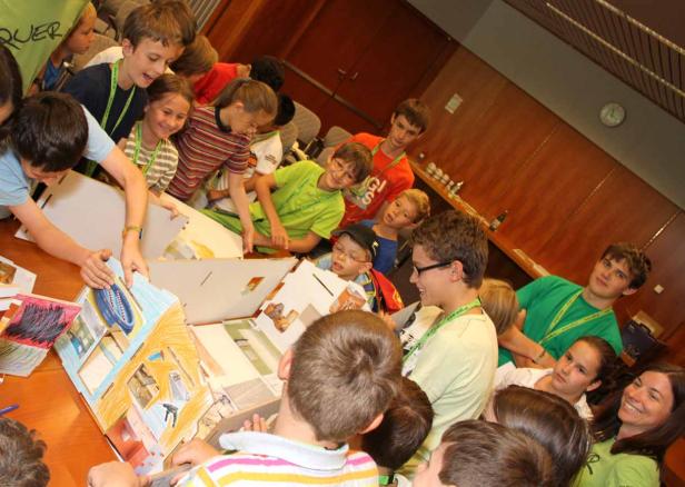 Eine Gruppe Kinder arbeitet an einem Modellhaus aus Pappe.