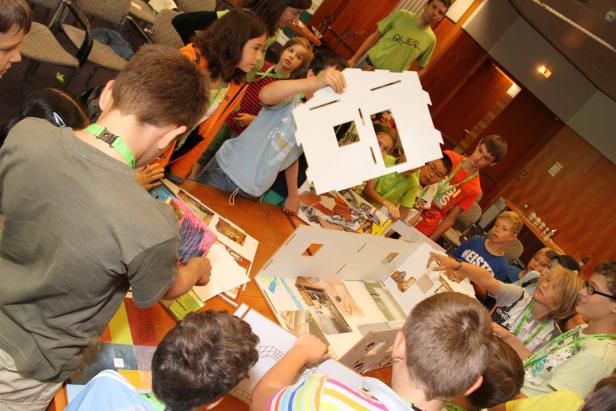 Eine Gruppe von Kindern arbeitet an einem Modellhaus aus Pappe.