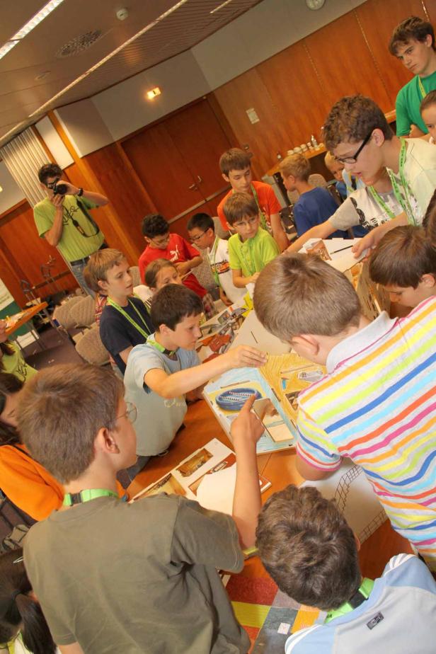 Eine Gruppe von Kindern arbeitet gemeinsam an einem Kunstprojekt an einem Tisch.