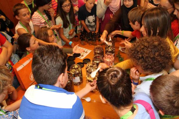 Eine Gruppe Kinder steht um einen Tisch und füllt Süßigkeiten in Gläser.