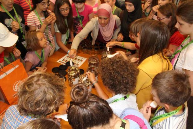 Eine Gruppe Kinder füllt Behälter mit Süßigkeiten an einem Tisch.