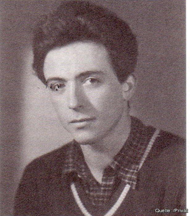 Ein junger Mann mit dunklen Haaren und einem Hemd mit V-Ausschnitt.