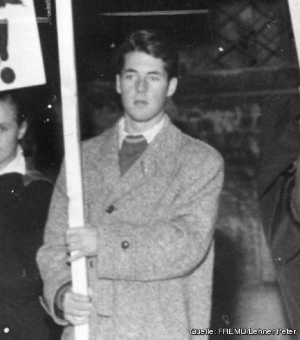 Ein junger Mann hält ein Schild bei einer Demonstration.