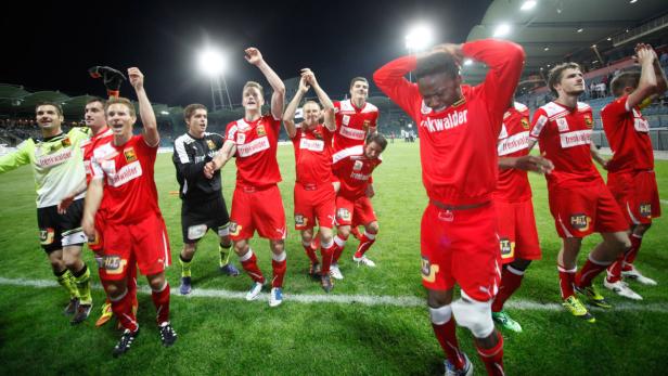 Eine Fußballmannschaft feiert auf dem Rasen ihren Sieg.