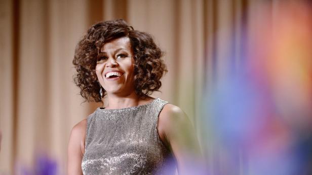 Michelle Obama lächelt in einem silbernen Kleid.