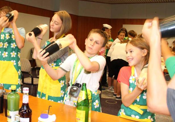 Kinder mixen Cocktails in Cocktailshakern bei einem Workshop.