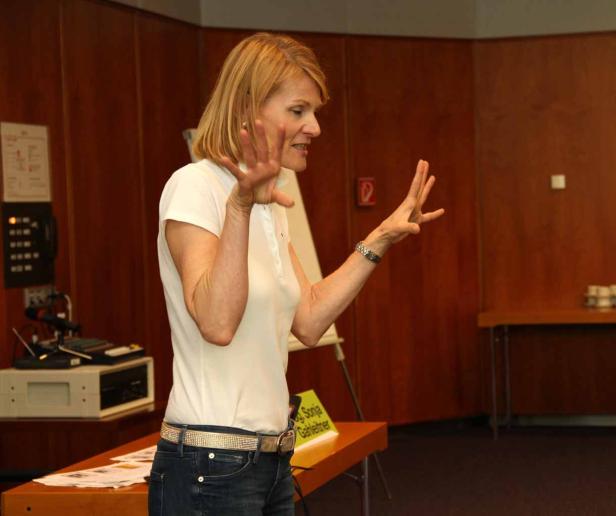 Sonja Gahlertner hält einen Vortrag mit erhobenen Händen.