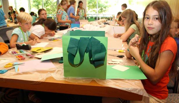 Eine Gruppe Kinder bastelt an einem Tisch mit Papier und Scheren.