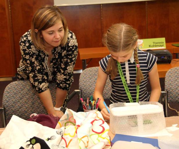 Eine Frau und ein Mädchen basteln an einem Tisch mit verschiedenen Materialien.