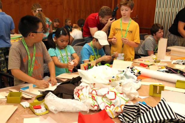 Kinder basteln gemeinsam an einem Tisch mit verschiedenen Materialien.