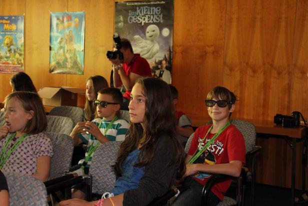 Kinder sitzen im Kino, einige tragen 3D-Brillen.