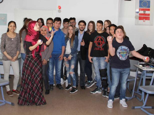 Eine Gruppe von Jugendlichen steht in einem Klassenzimmer und jongliert.