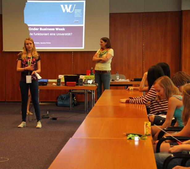 Eine junge Frau präsentiert während der Kinder Business Week, wie eine Universität funktioniert.