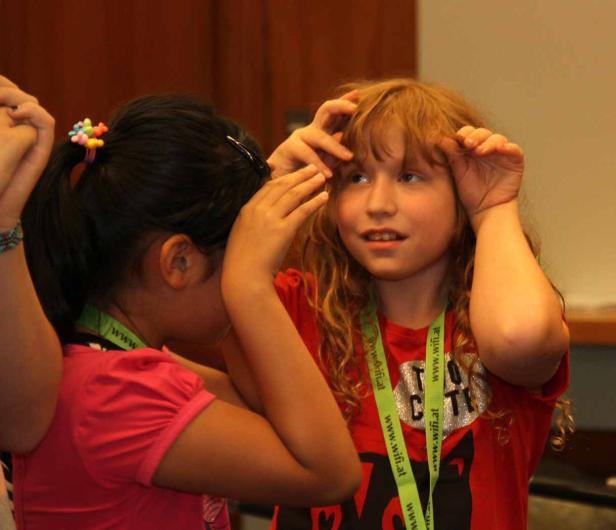 Zwei Mädchen spielen mit ihren Händen vor ihren Gesichtern.