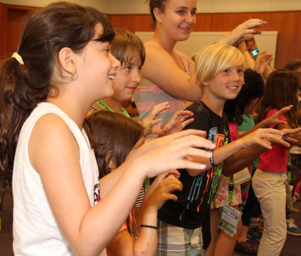 Eine Gruppe Kinder streckt die Hände in einem Raum aus.