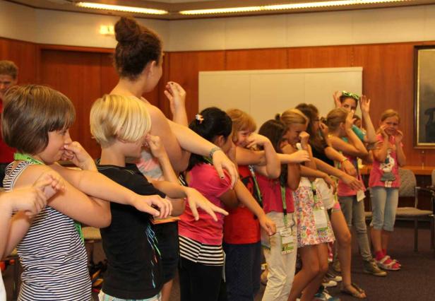 Eine Gruppe Kinder steht in einer Reihe und macht eine Übung.