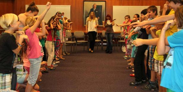 Zwei Gruppen von Kindern stehen sich gegenüber und ahmen mit ihren Händen Tiere nach.