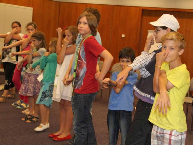 Eine Gruppe Kinder steht in einer Reihe und berührt ihre Nasen.
