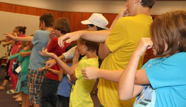 Eine Gruppe von Kindern steht in einer Reihe und macht Dehnübungen.
