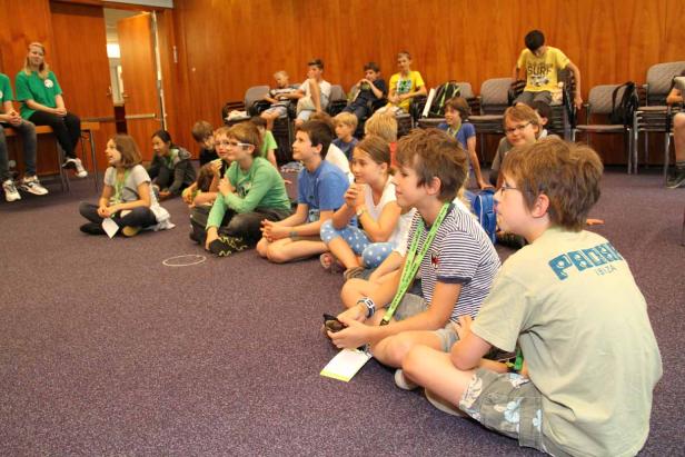 Eine Gruppe Kinder sitzt auf dem Boden und hört aufmerksam zu.