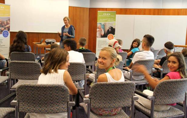 Eine Frau hält einen Vortrag vor einer Gruppe von Kindern in einem Raum.