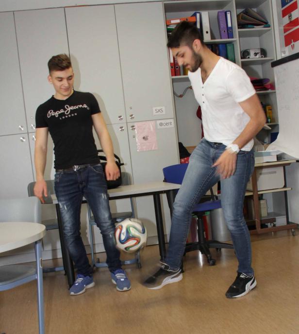 Zwei junge Männer spielen in einem Raum mit einem Fußball.