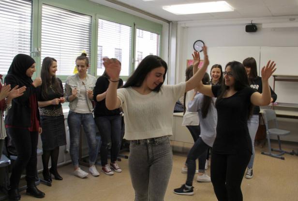 Eine Gruppe junger Frauen tanzt und klatscht in einem hellen Raum.
