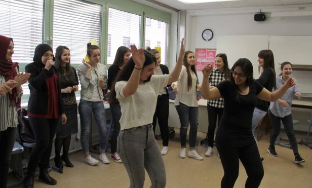 Eine Gruppe junger Frauen tanzt in einem Klassenzimmer.