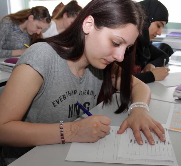 Mehrere Schüler sitzen in einem Klassenzimmer und schreiben an ihren Tischen.