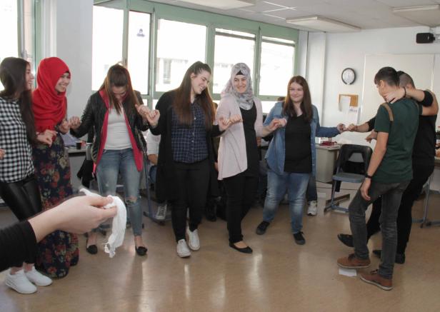 Eine Gruppe junger Leute hält Händchen und bildet einen Kreis in einem Raum.