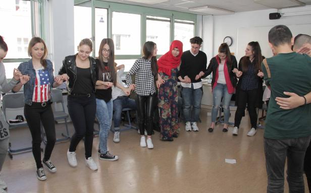 Eine Gruppe junger Leute steht im Kreis und hält Händchen.