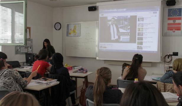 Schüler sitzen in einem Klassenzimmer und schauen einem Vortrag von Merdan Biter zu.