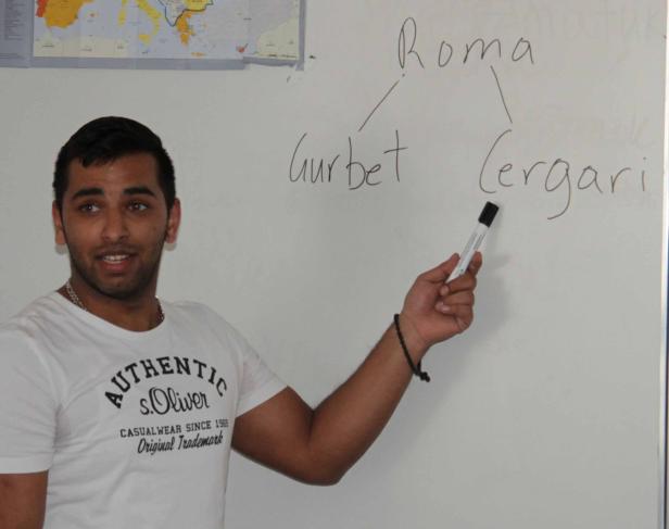 Ein junger Mann erklärt die Wörter „Gurbet“ und „Cergari“ in Bezug auf „Roma“ an einer Tafel.