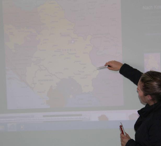Eine Frau zeigt mit einem Stift auf eine Karte des Balkans.