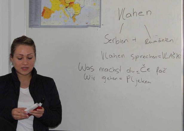 Eine Frau steht vor einer Tafel mit Notizen über Vlachen, Serbien und Rumänien.